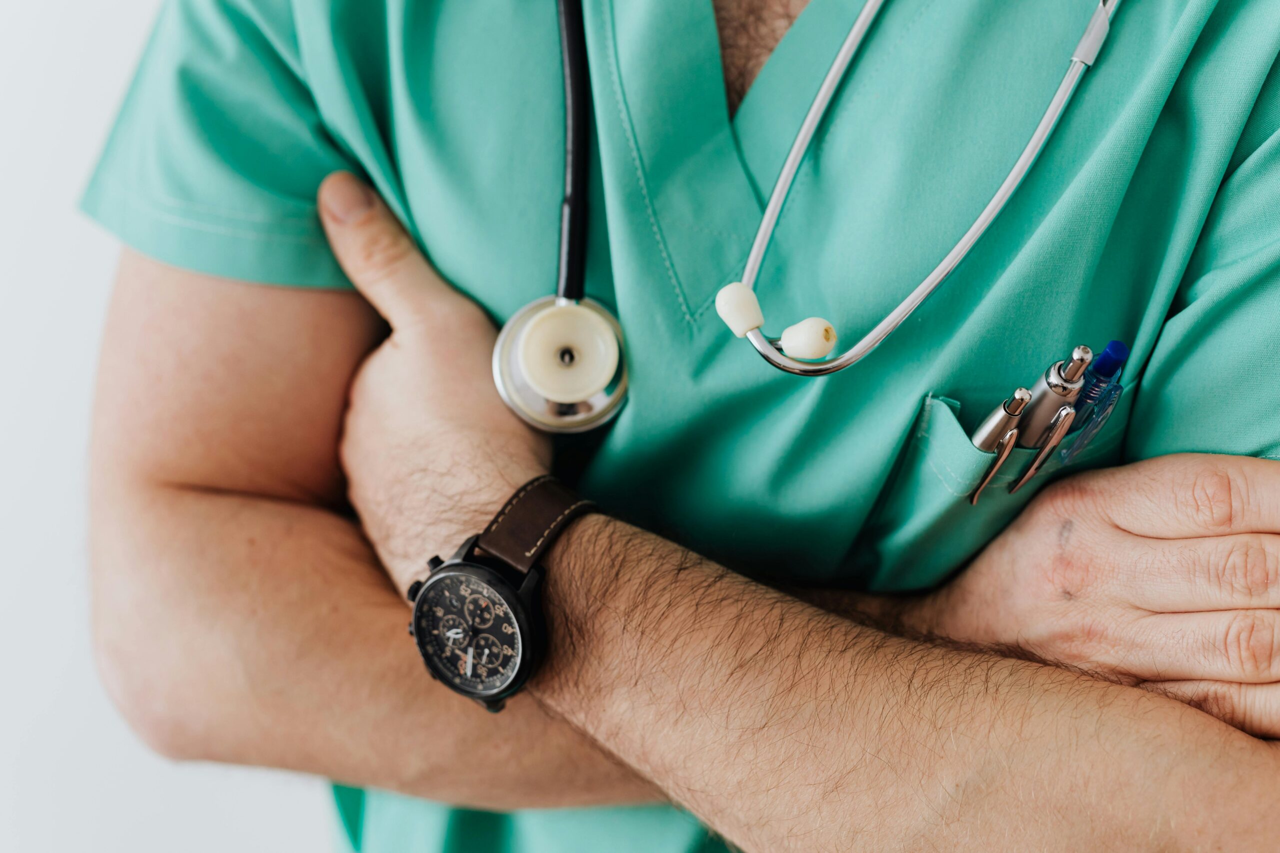 Torso image of person with arms folded across medical smock